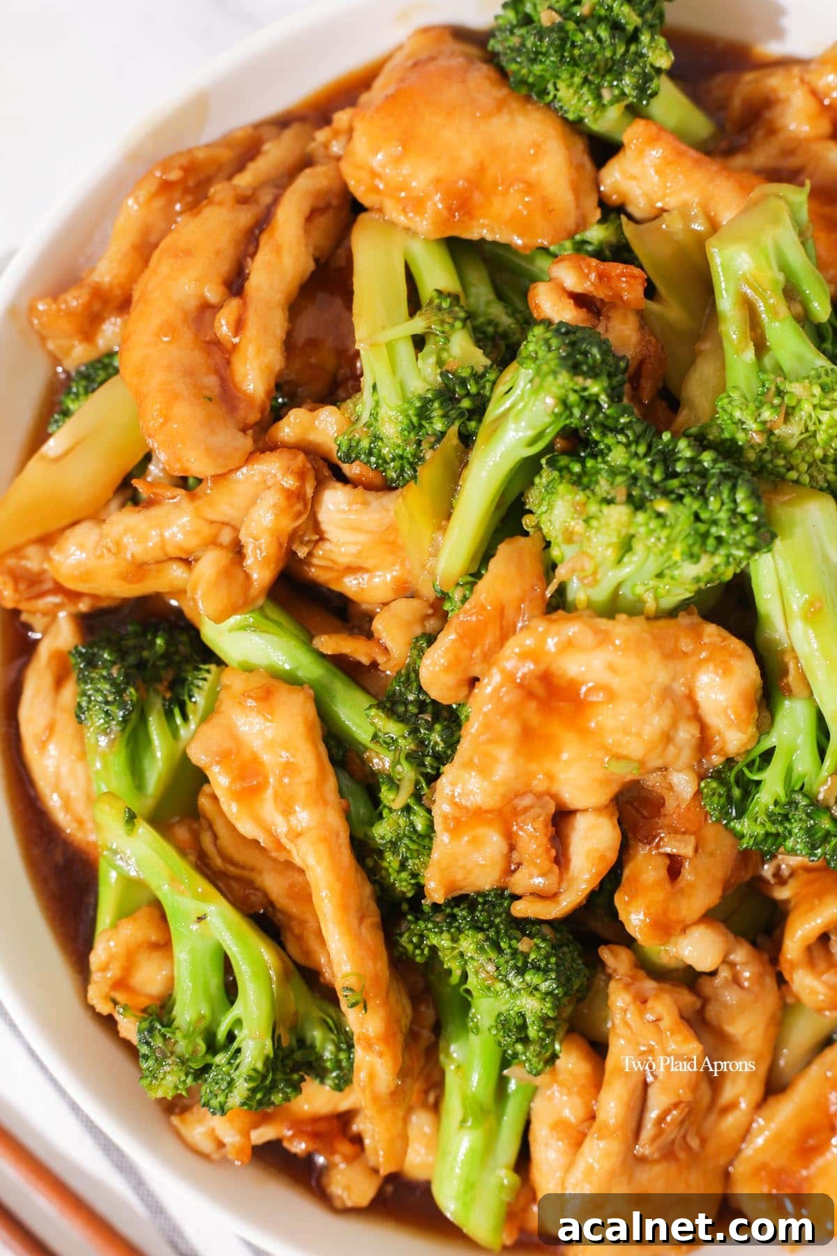 Close up of a plate of chicken and broccoli tossed in a brown sauce.