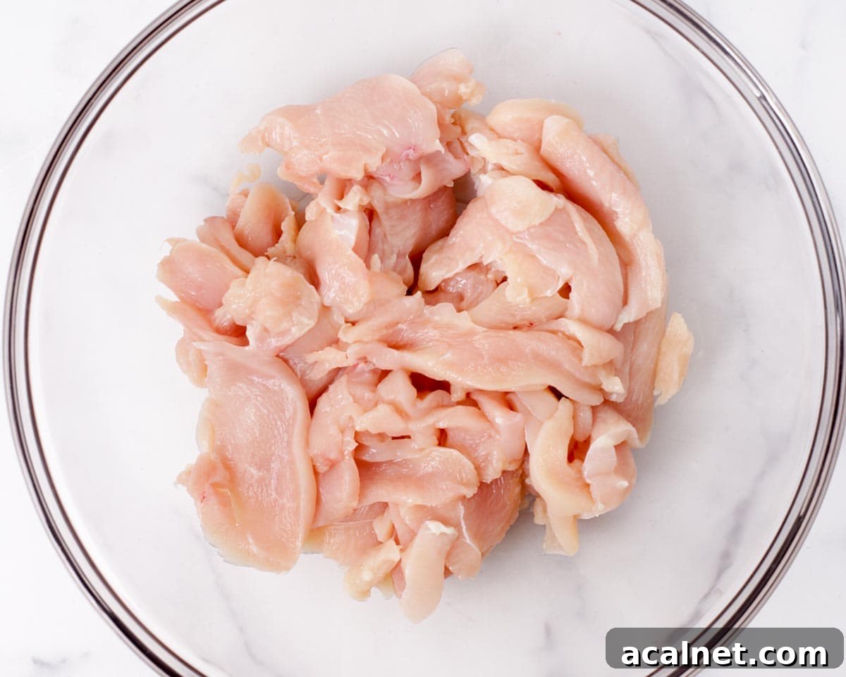 Adding sliced chicken and seasonings in a bowl.