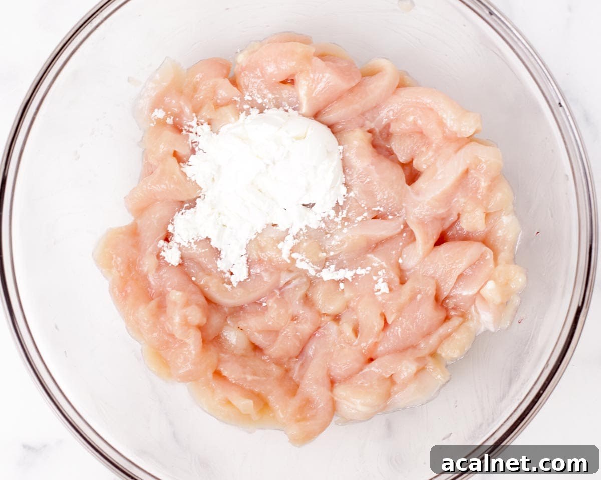 Adding cornstarch to seasoned chicken.