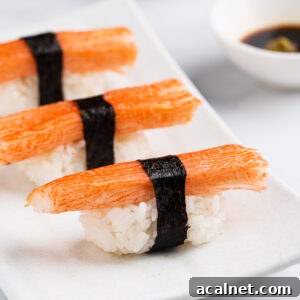 Kanikama nigiri on a white plate with soy sauce and wasabi.
