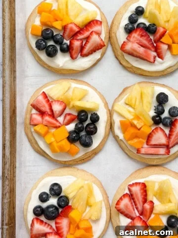 a few of the sugar cookie fruit pizzas on a cookie sheet.