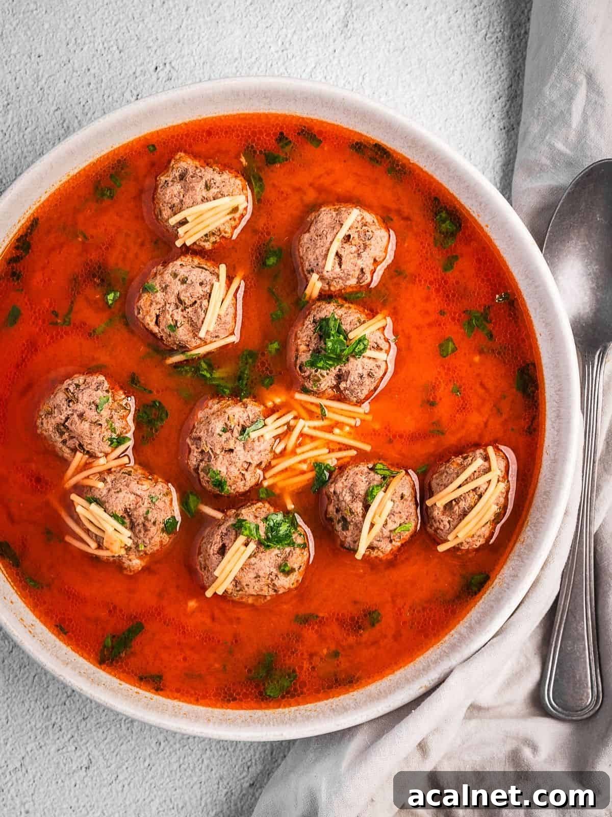 Bowl of kofta meatball soup with noodles in a tomato broth.