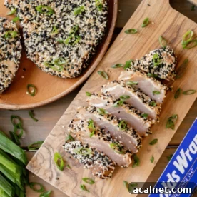 Grilled and sliced tuna steak on a wooden cutting board.
