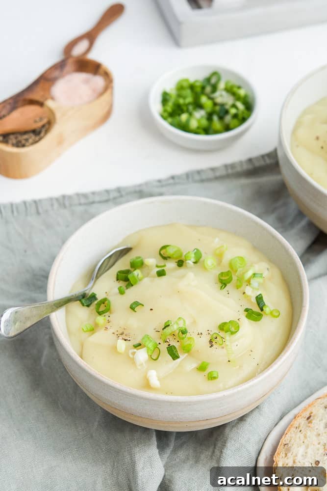 bowl of soup, sitting on a grey towel, with some spoons on the side, salt and pepper and bread in the background.