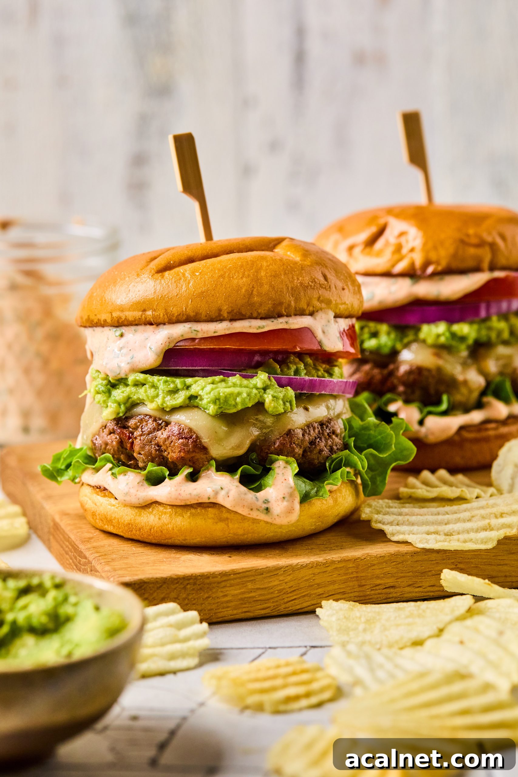 Smoky Chipotle Beef Burgers with Creamy Aioli 11 2 chipotle beef burgers slathering in homemade chipotle aioli sitting on a wood tray surrounded by crinkle potato chips