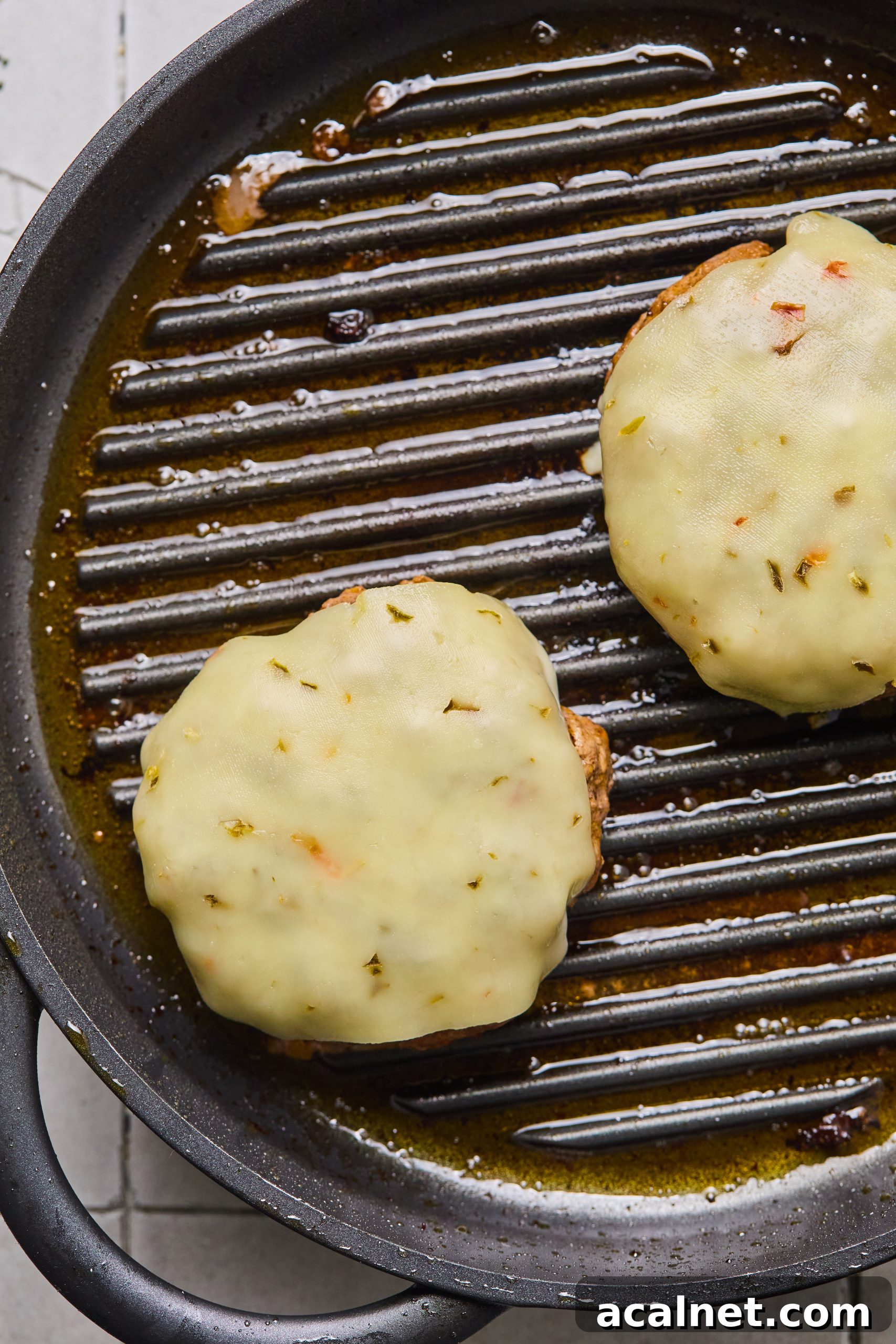 Smoky Chipotle Beef Burgers with Creamy Aioli 10 2 large grilled beef burger patties topped with melted pepper jack cheese sitting on a grill pan