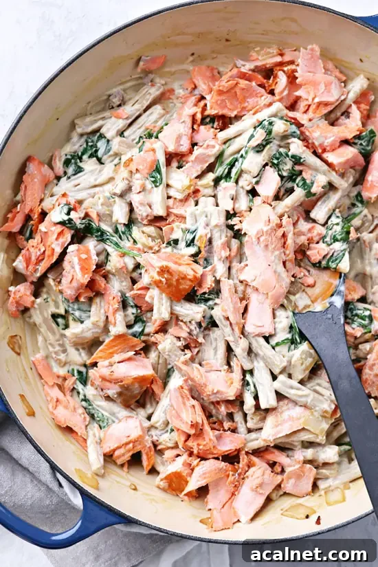 A blue skillet filled with Dairy Free Creamy Salmon Pasta.