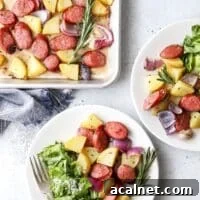 An above view of two plates of sheet pan sausage and potatoes with side salads