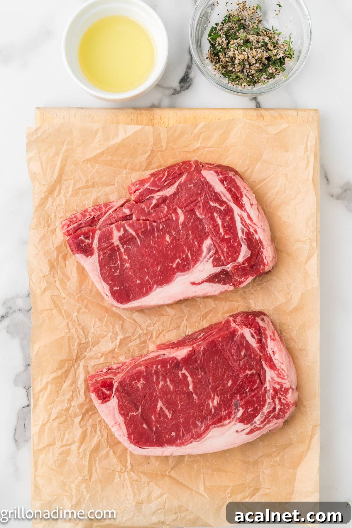 Steak on parchment paper with a bowl of melted butter and fresh herbs