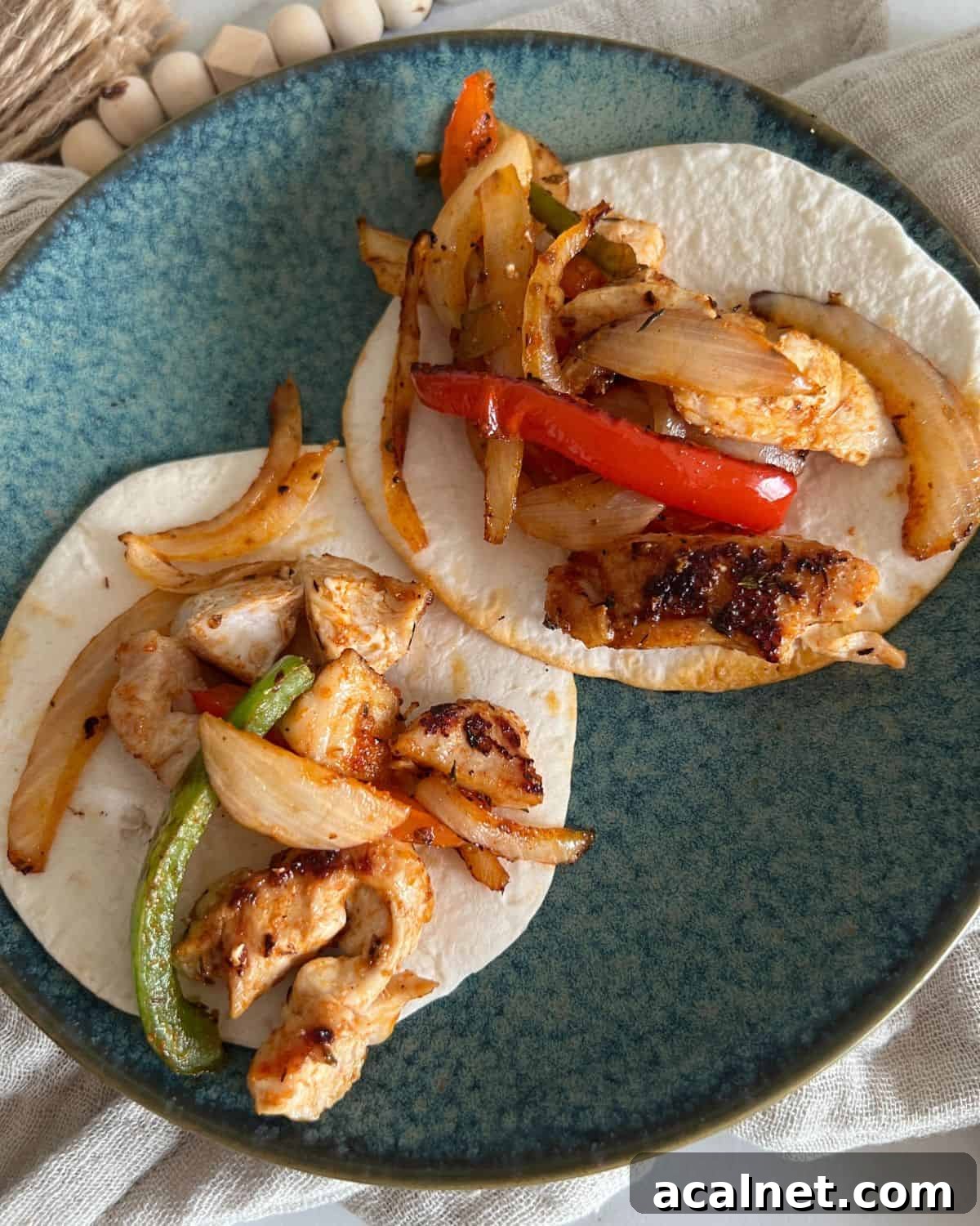 Two chicken fajitas on street style tortillas on a blue plate.