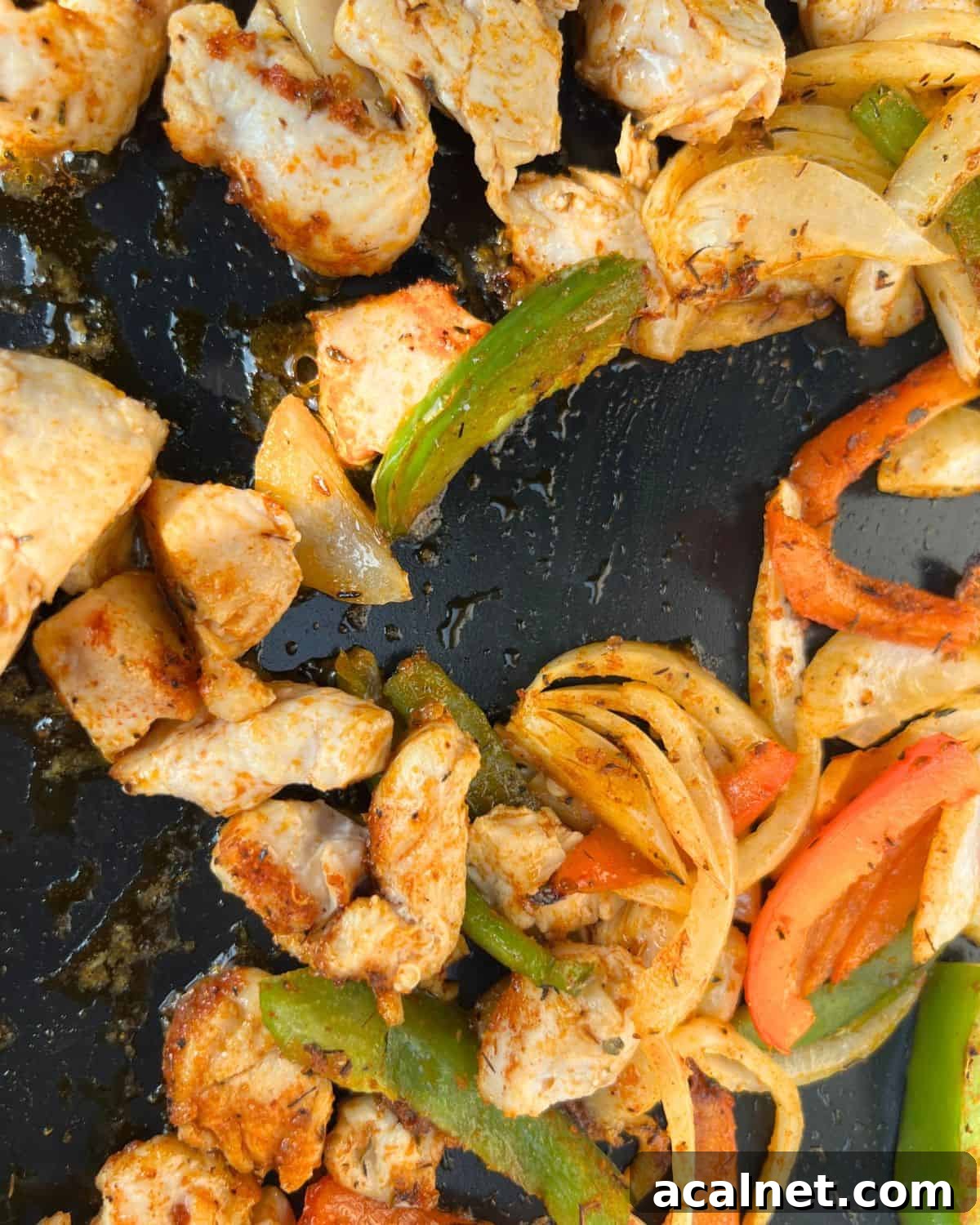 Cooked seasoned chicken and vegetables on a griddle.