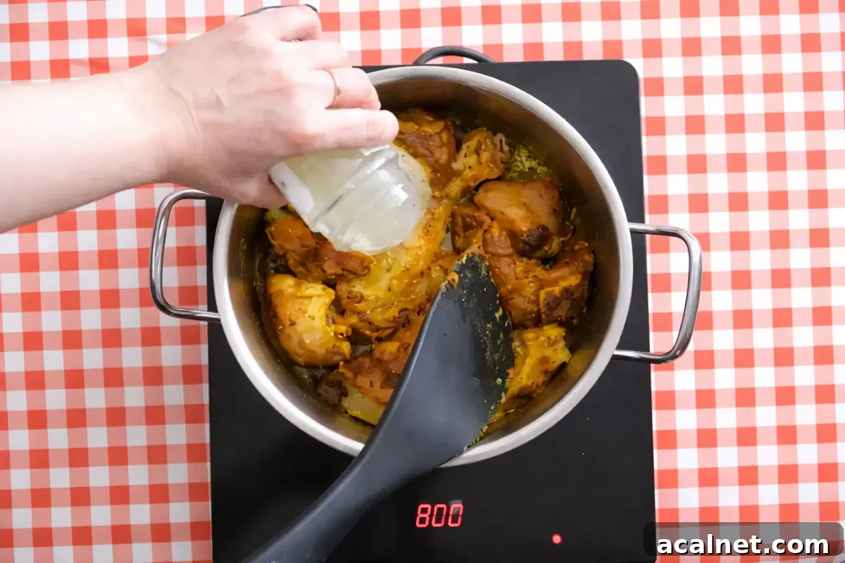 Low FODMAP Chicken Curry for Sensitive Stomachs 6 Chicken broth poured over spiced chicken while stirring.