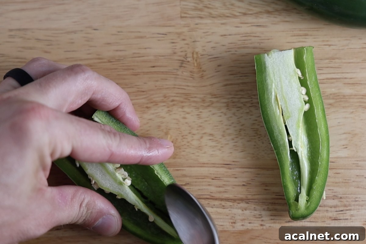 Removing the seeds and ribs from a jalapeno that has been sliced in half.