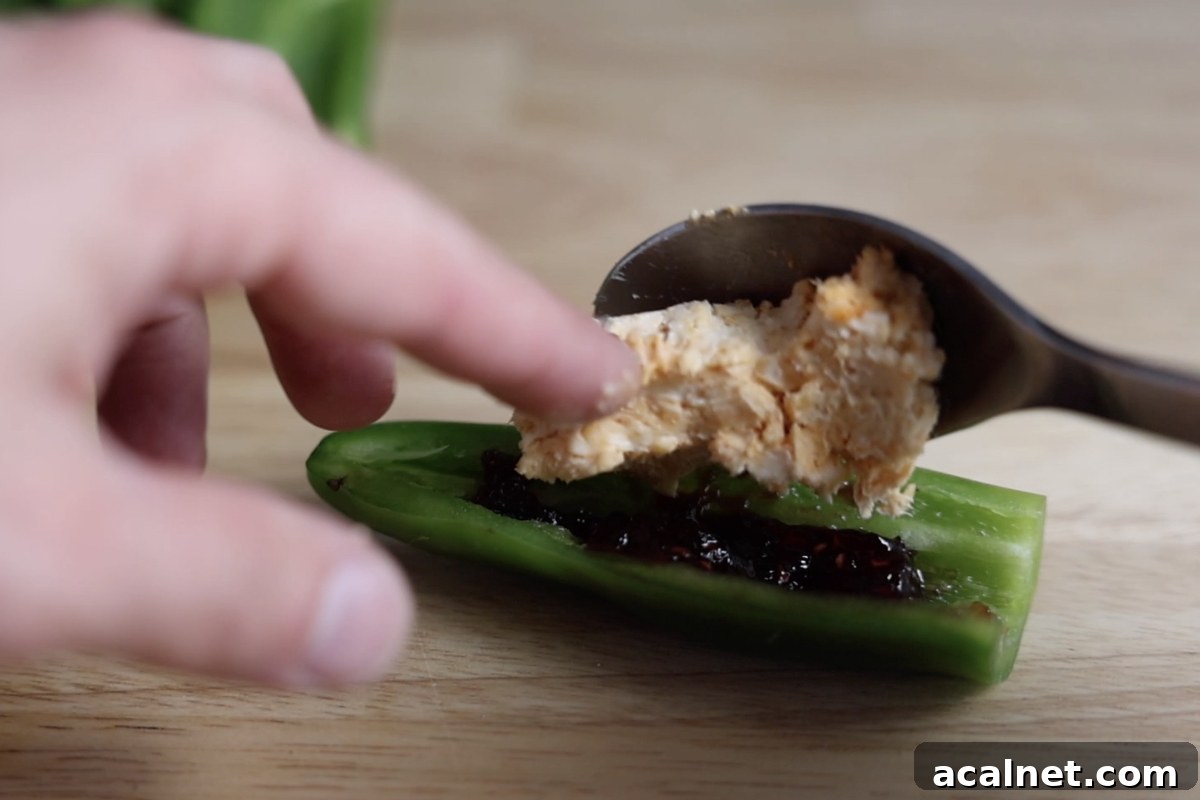 Stuffing a jalapeno with raspberry jam and cheese filling.
