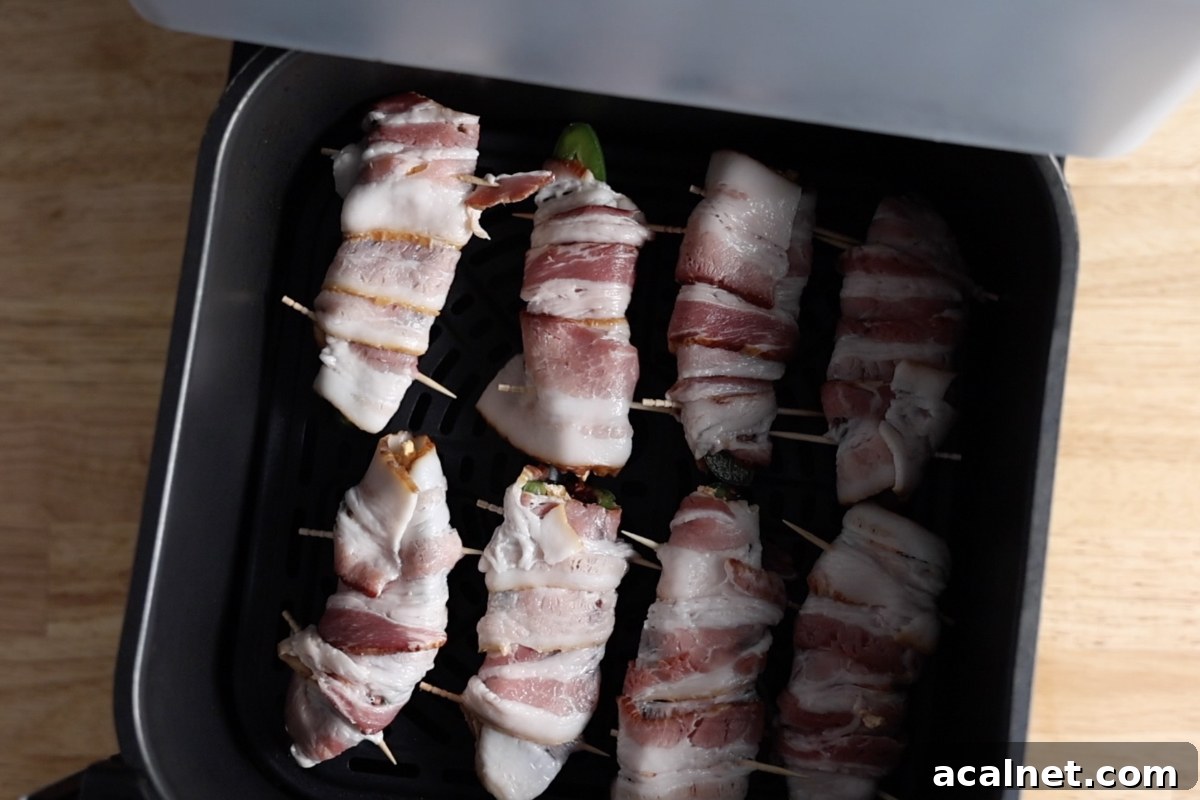 Cooking air fryer bacon wrapped jalapeno poppers in an air fryer.