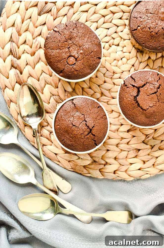 Four baked chocolate puddings, with spoons on a raffia mat viewed from above