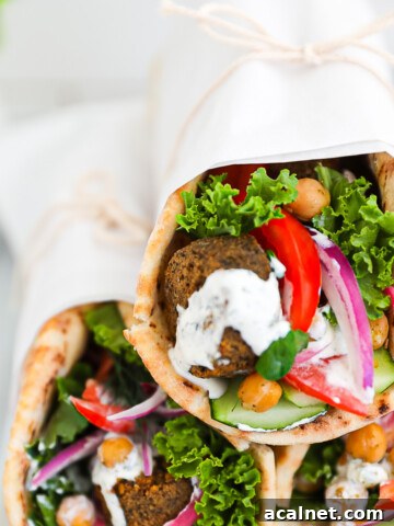 Three vegetable gyros stacked on top of each other and wrapped in white parchment paper.