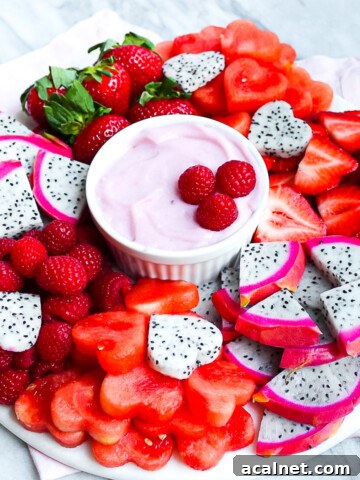 A fruit platter with fresh berries, melon, and dragon fruit with a homemade fruit dip in the center.