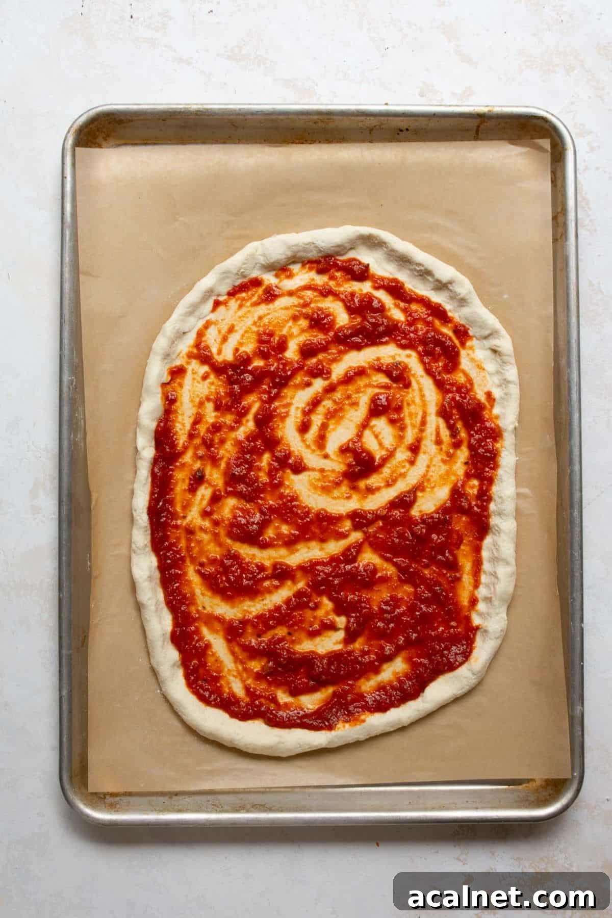 Homemade Greek Yogurt Pizza Dough: Soft, Quick Recipe 10 Spreading pizza sauce over Greek Yogurt Pizza Dough before adding toppings.