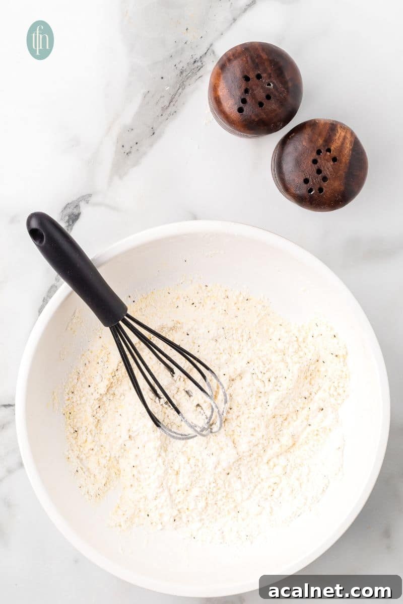 A bowl of dry ingredients with whisk.