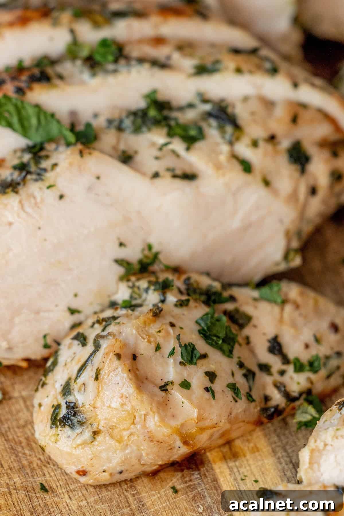 Sliced grilled chicken breast garnished with chopped herbs on a wooden cutting board, reminiscent of an easy turkey recipe like baked turkey tenderloin for a simple yet flavorful meal.