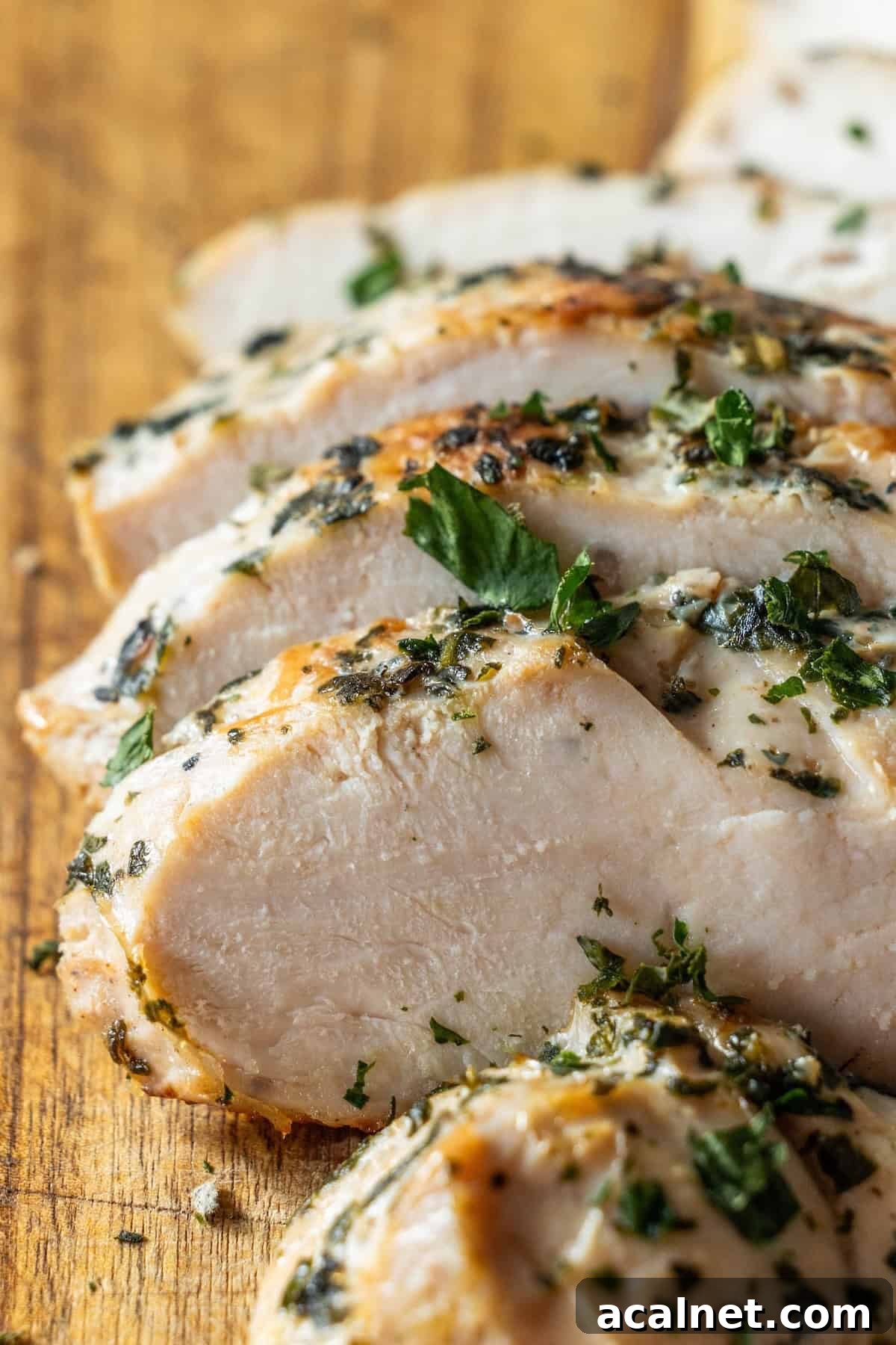 Sliced cooked chicken breast garnished with chopped herbs on a wooden cutting board, perfect as inspiration for your next Easy Turkey Recipe or Baked Turkey Tenderloin dish.