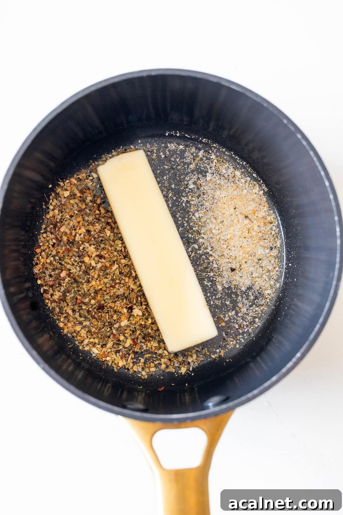 A saucepan containing a stick of butter, a pile of mixed dried herbs and spices, and a separate pile of granulated seasoning—perfect for starting any easy turkey recipe or flavoring baked turkey tenderloin.
