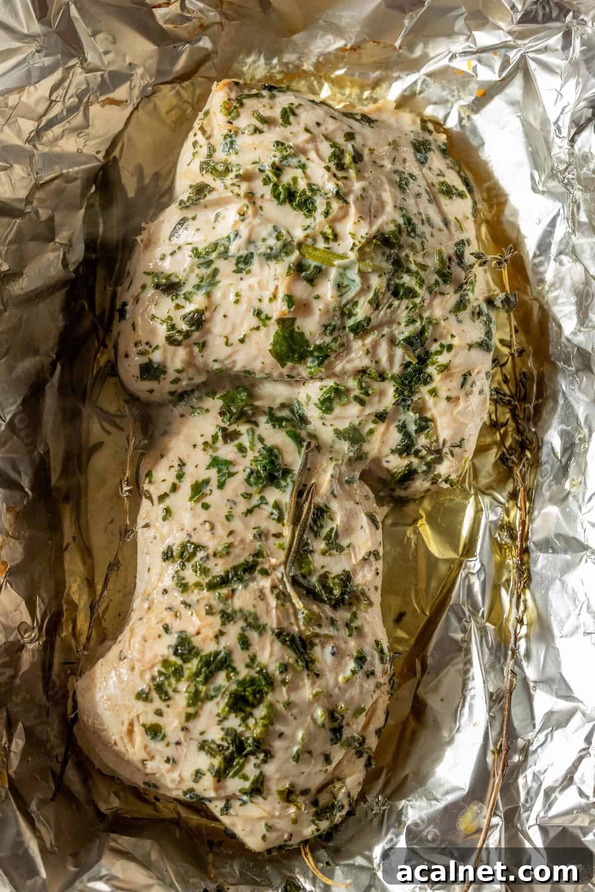 Cooked chicken breasts seasoned with herbs and spices, resting on crumpled aluminum foil with visible juices—perfect inspiration for an Easy Turkey Recipe like baked turkey tenderloin.