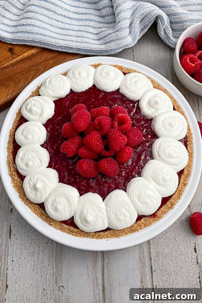assembled raspberry cream pie with a side dish of fresh raspberries