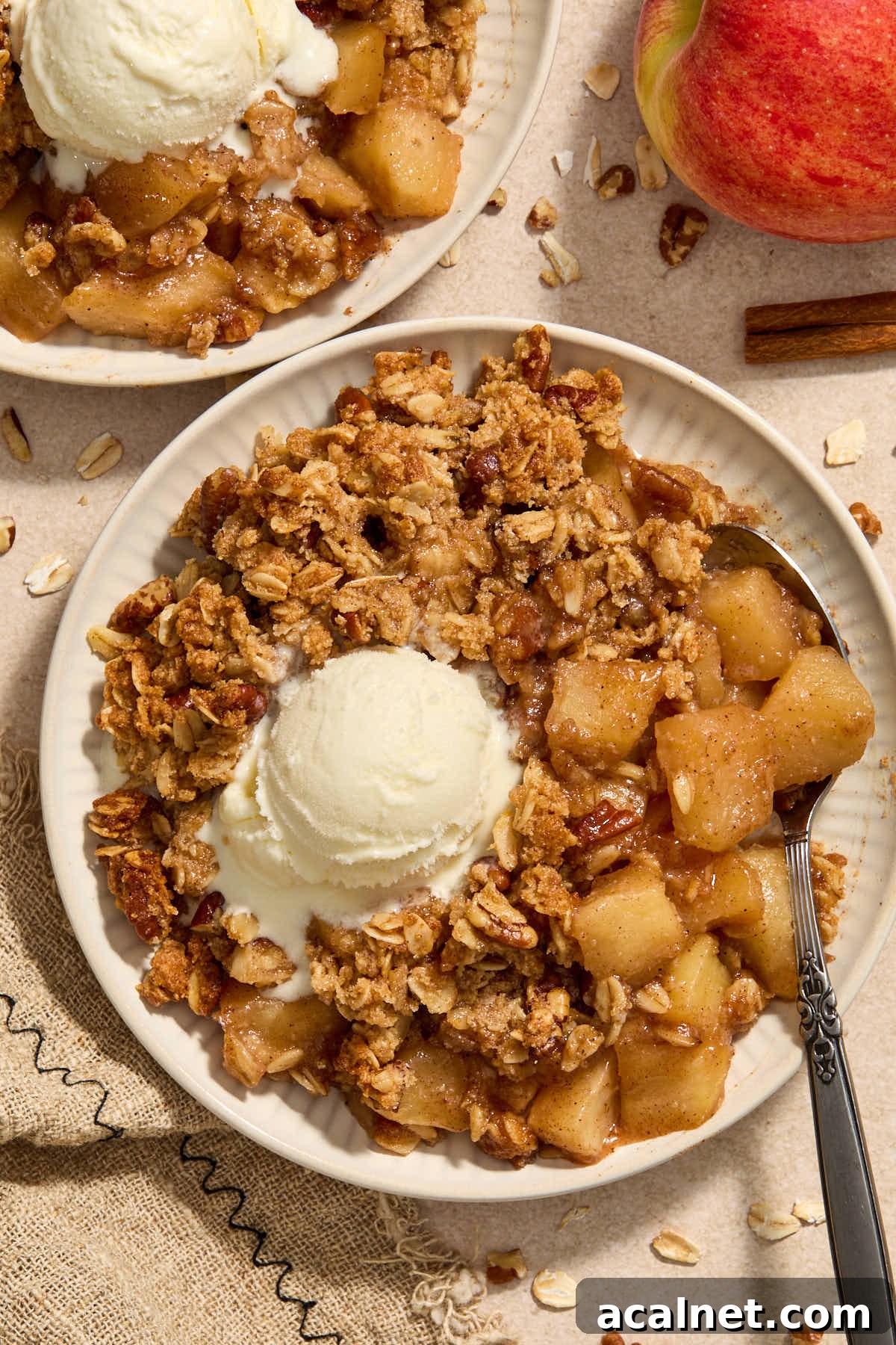 Apple crisp on a plate with vanilla ice cream on top.