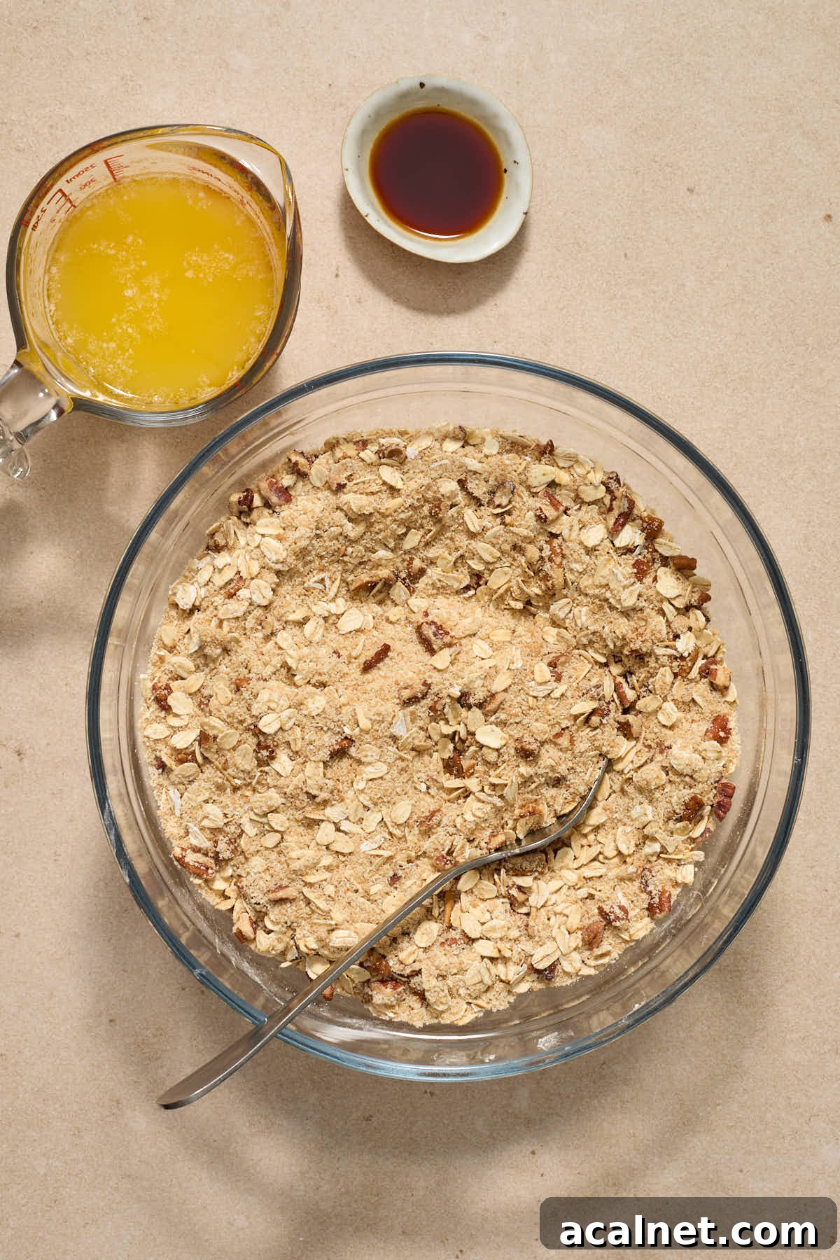 Dry crisp ingredients stirred together in a glass bowl with melted butter and vanilla on the side.