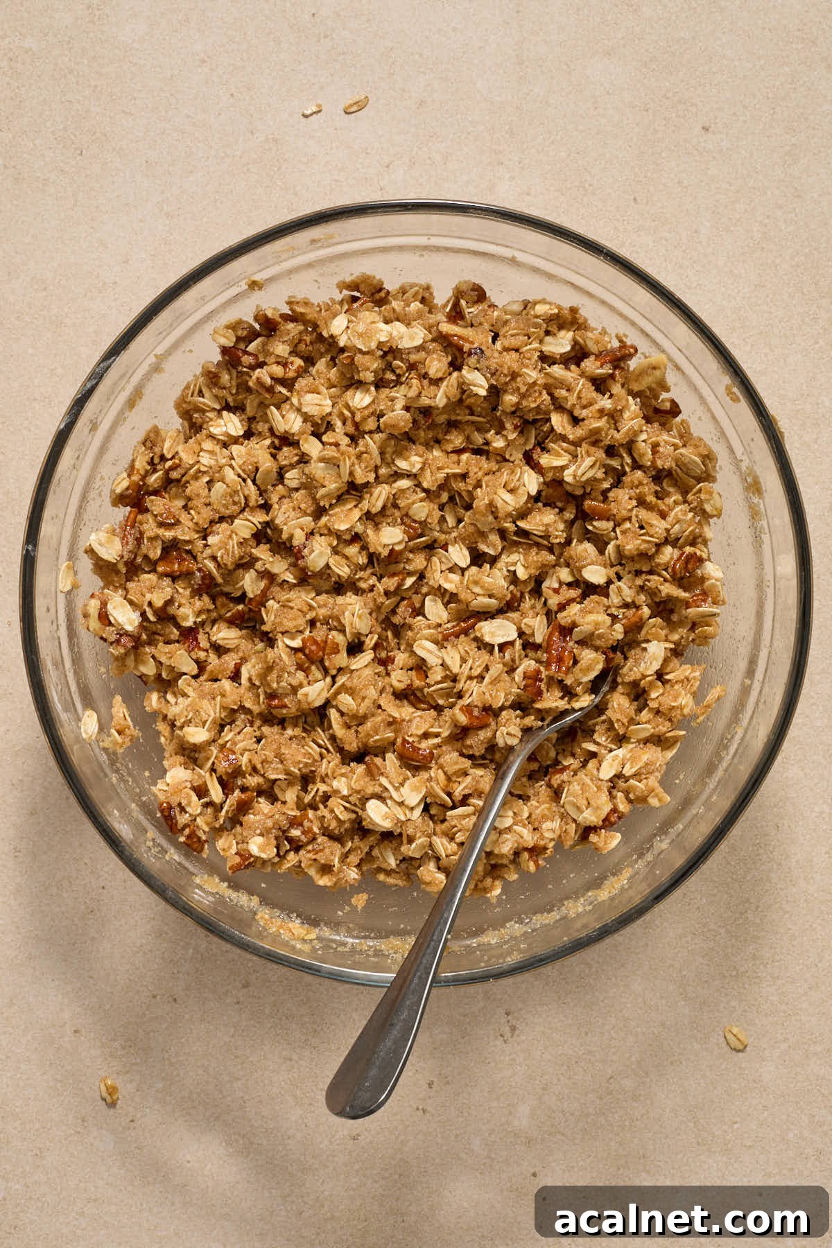 Crisp topping mixed together in a glass bowl with a fork.