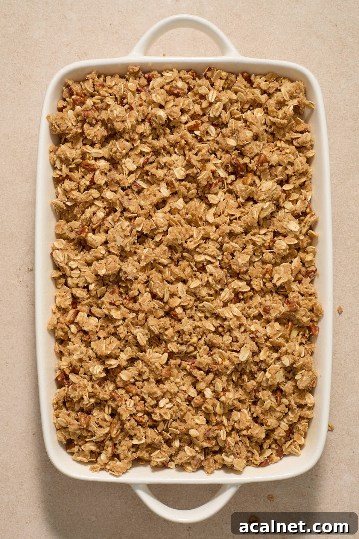Crisp topping layered on top of apples in baking dish.