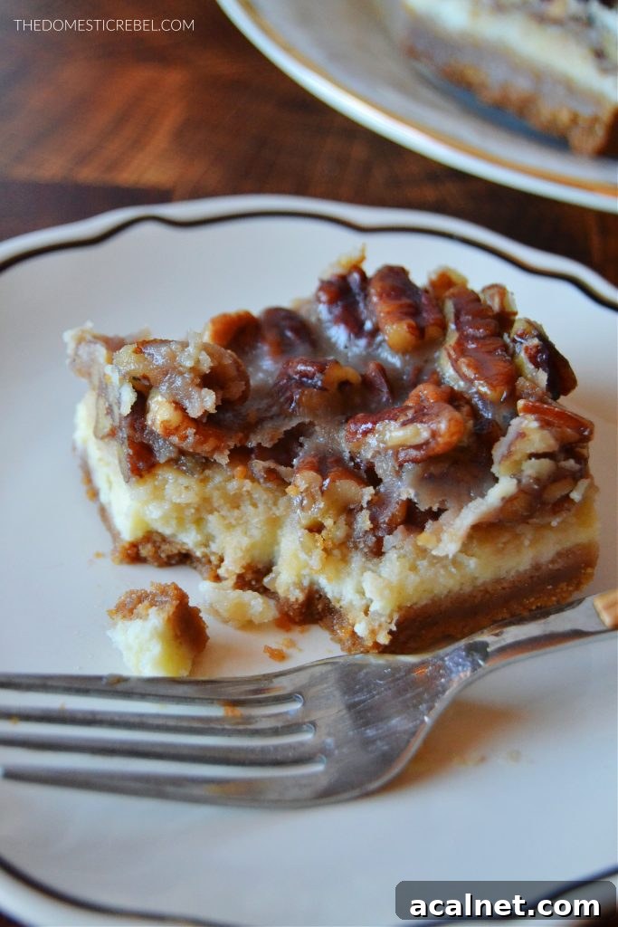 Pecan Pie Cheesecake Bars Recipe 6 a pecan pie cheesecake bar sits on a black and white plate with a metal fork. a bite has been taken out of the bar.