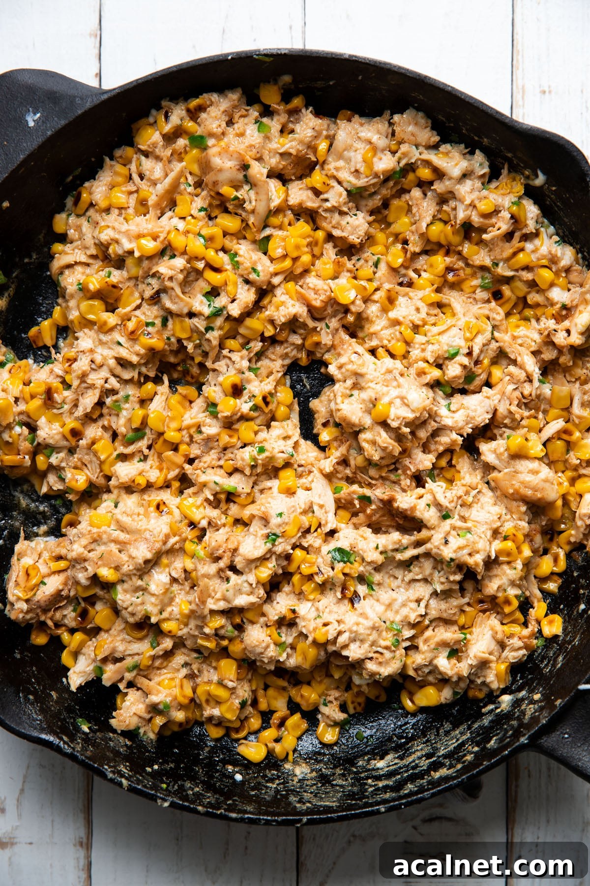 shredded chicken and mexican street corn mixed together in a skillet