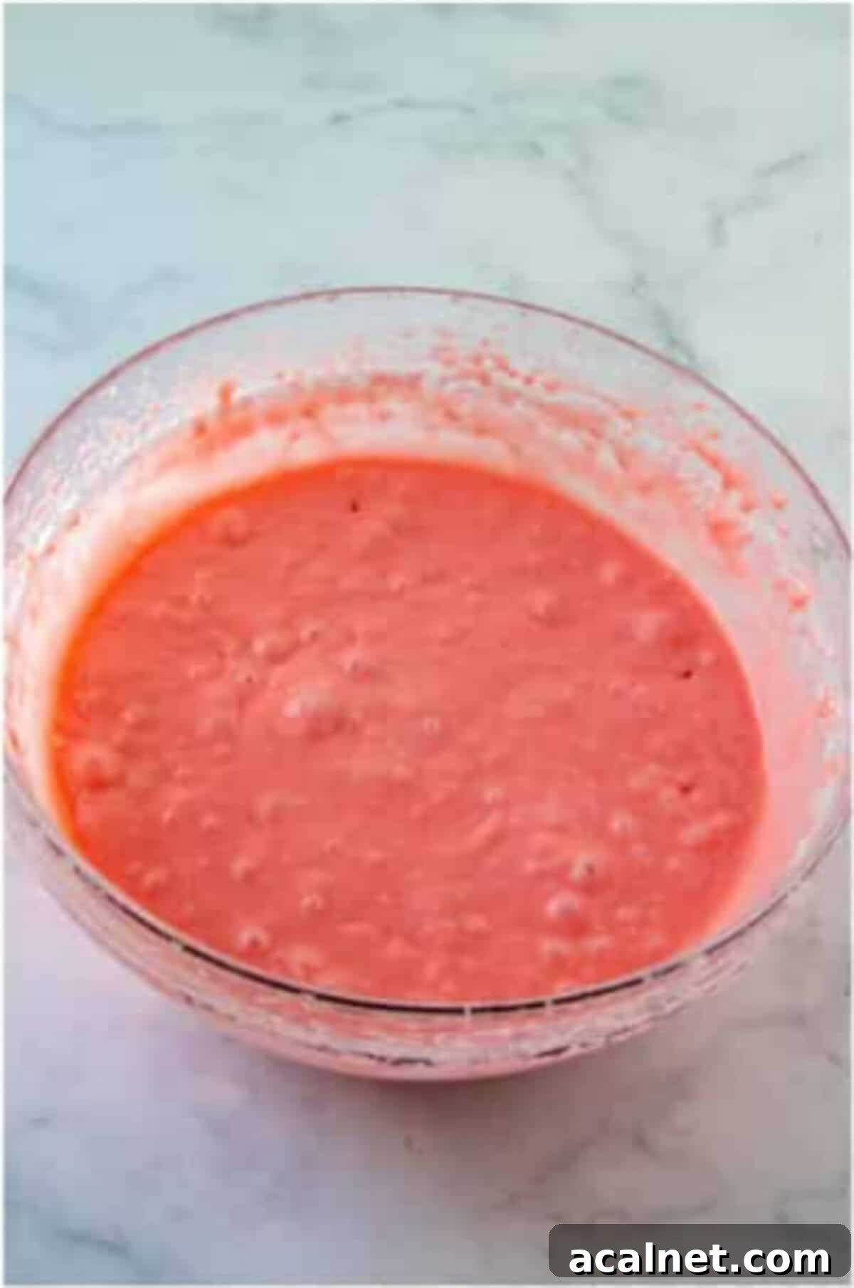 Pink strawberry cake batter mixed in a glass bowl.