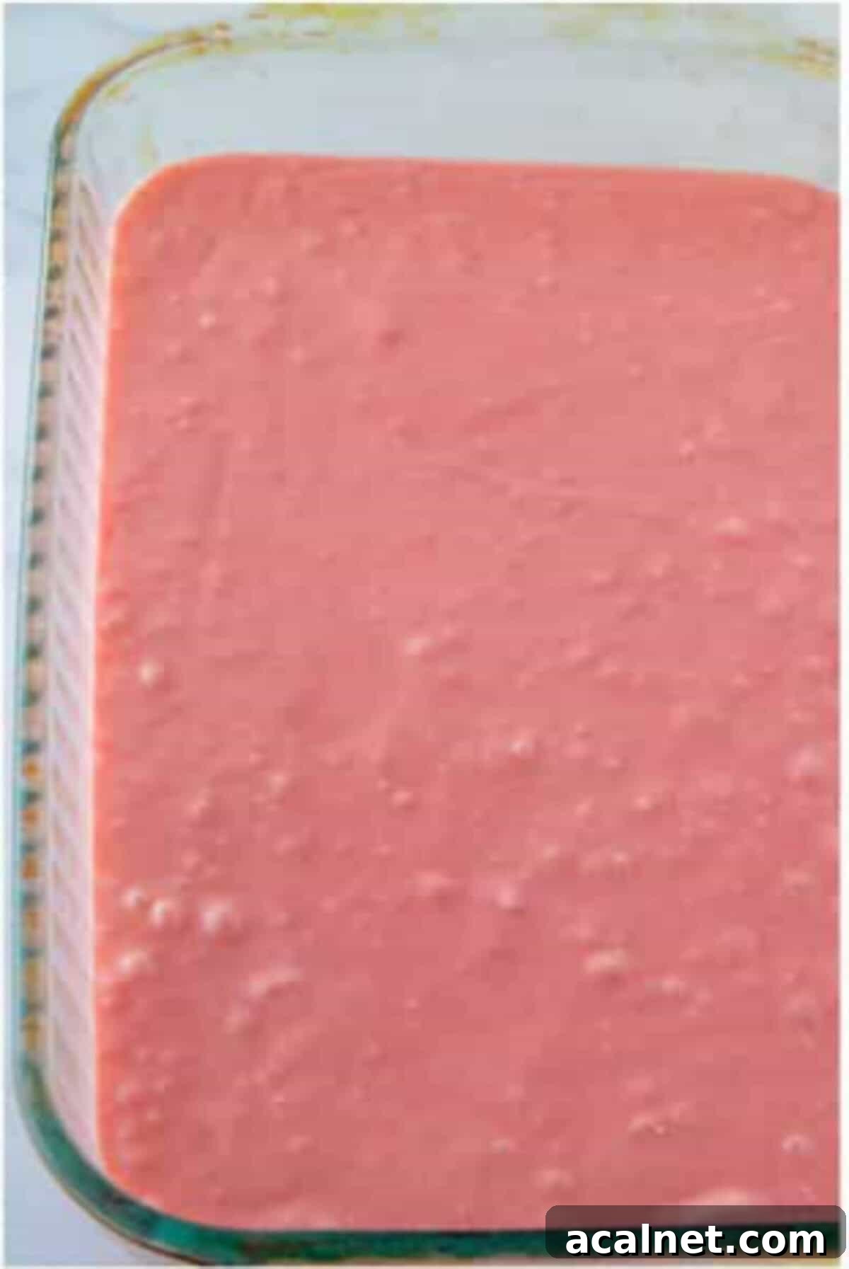Strawberry cake batter spread in a glass baking dish.