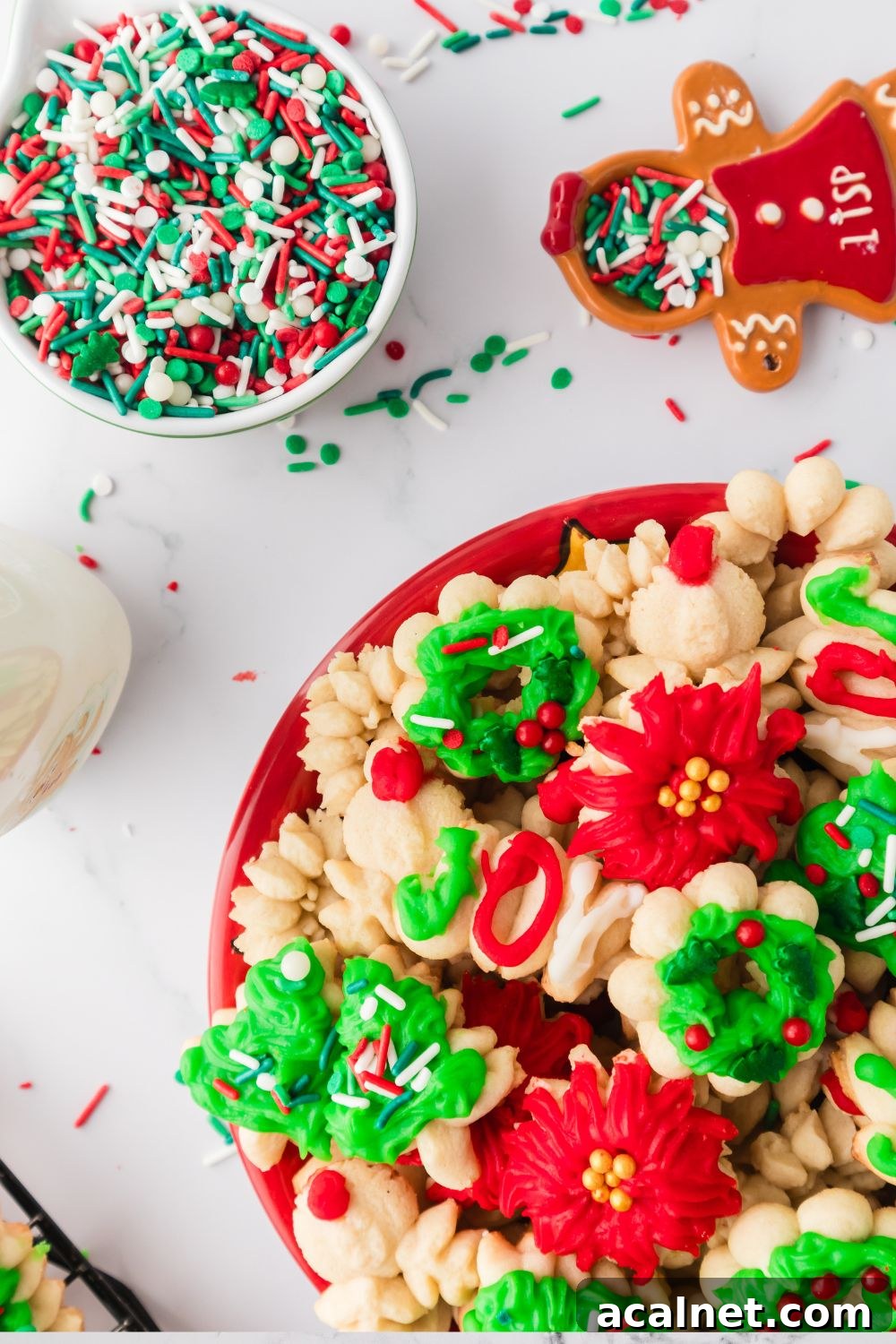 Classic Christmas Spritz Cookie Recipe 19 plate loaded with spritz cookies and sprinkles in a bowl to the side