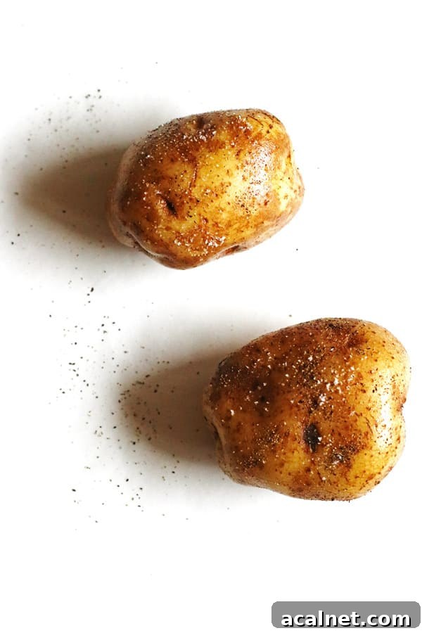 Potatoes rubbed with olive oil and sprinkled with salt and pepper on a white counter