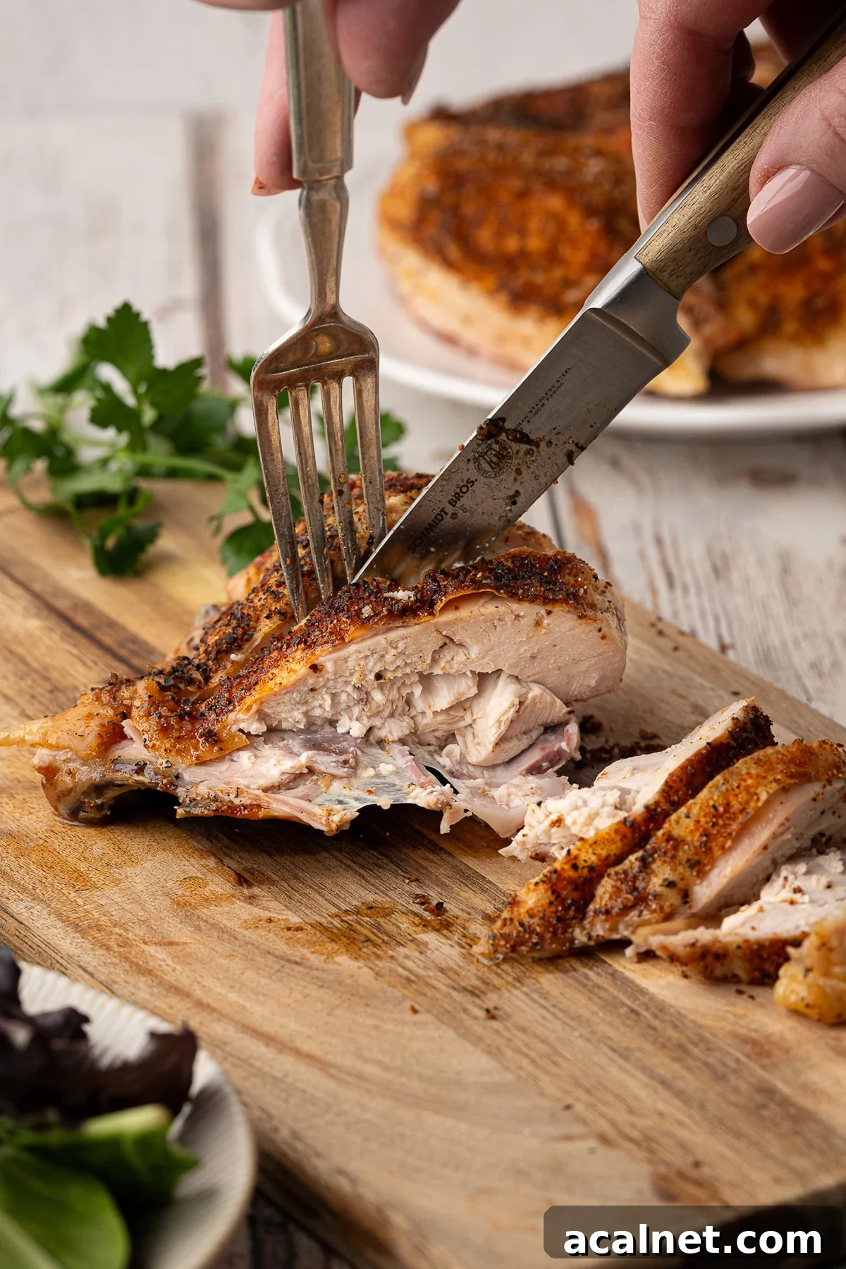 Slicing into the baked bone-in chicken breast on a wood cutting board.
