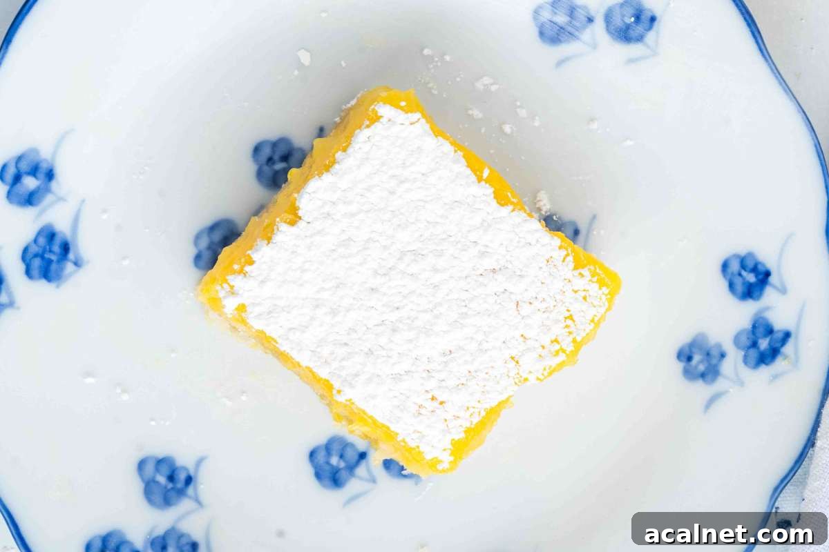 Side view of a sourdough lemon bar showing powdered sugar, bright lemon filling, and a crumbly crust.