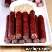 Venison snack sticks stacked on a white serving platter.