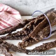 Homemade venison jerky in a glass that is on its side.