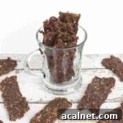 Strips of ground beef jerky on a white table and in a clear glass.