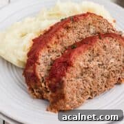 Two slices of venison meatloaf on a plate with mashed potatoes.