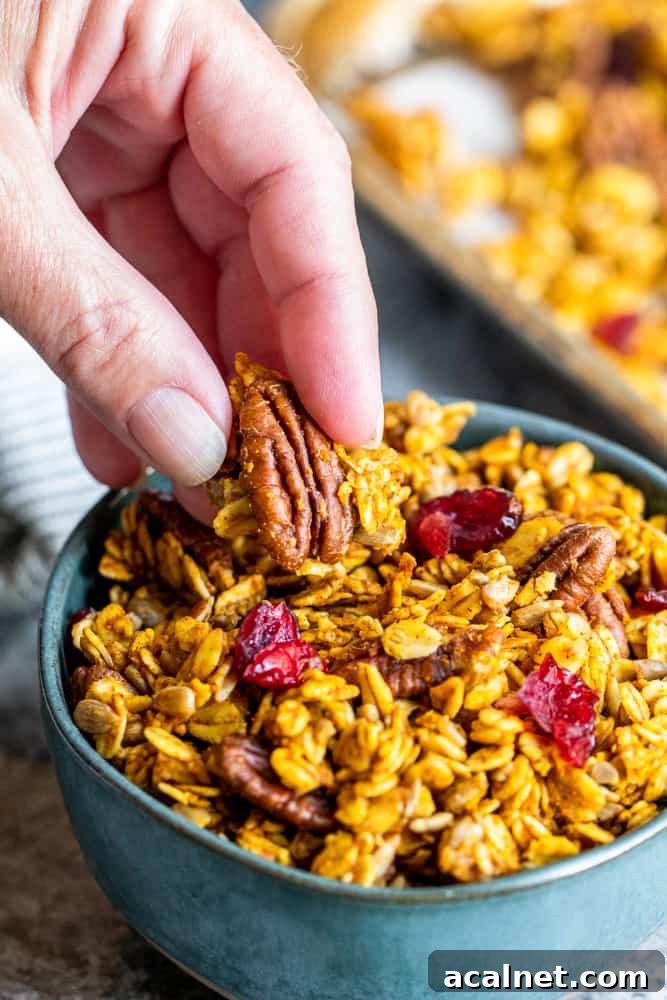 Handpicking up granola out of blue bowl.