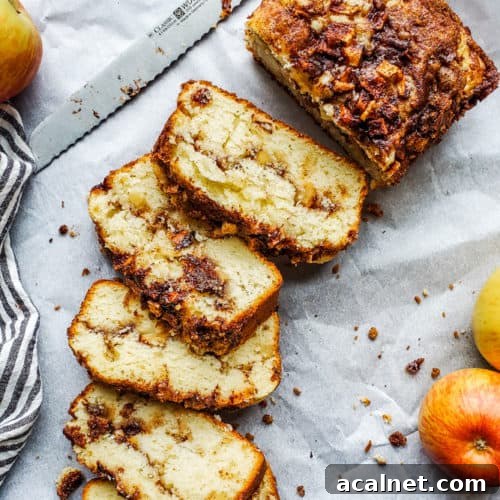 Apple bread laid out on white parchment paper and partially sliced.