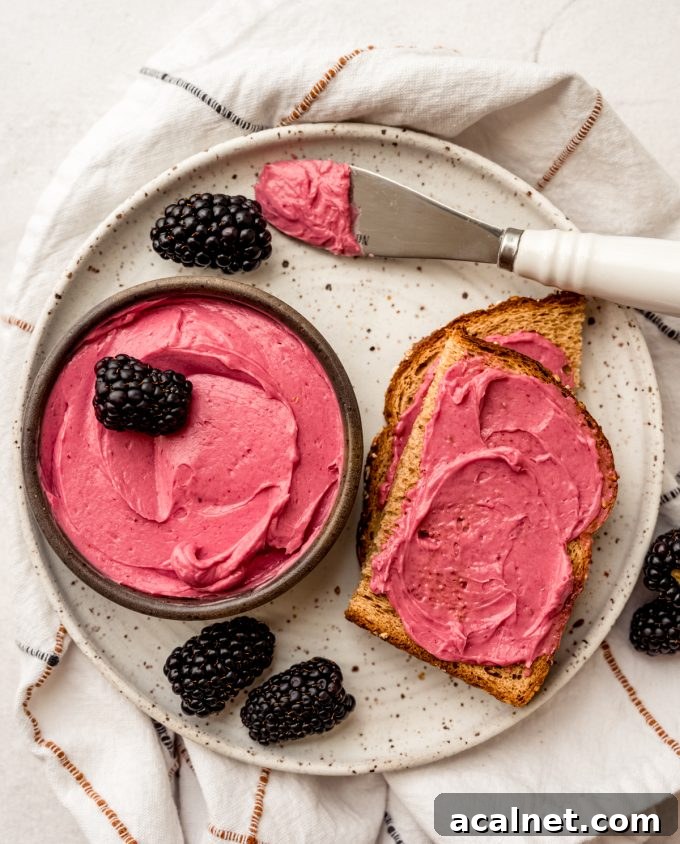 Aerial photo of blackberry butter in a bowl with a slice of toast that has some spread on it.