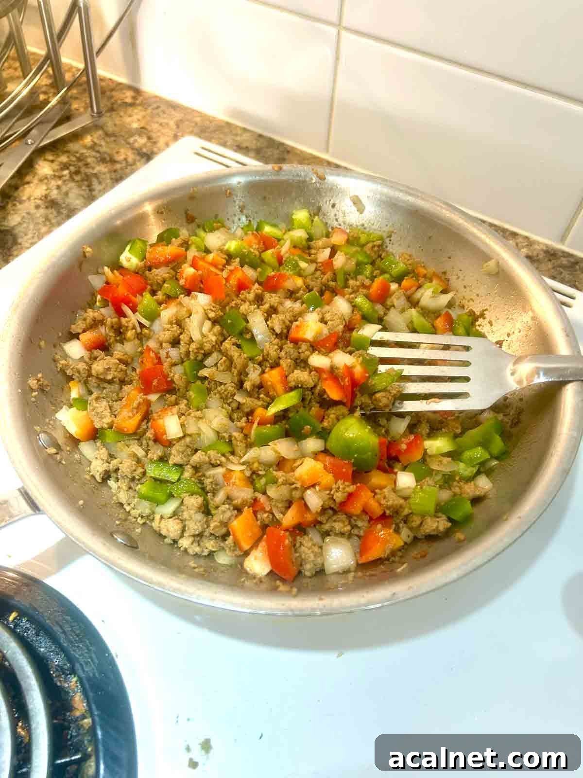 Hearty Breakfast Casserole with Sausage and Cheese 6 bell peppers mixed with sausage and onions in pan.