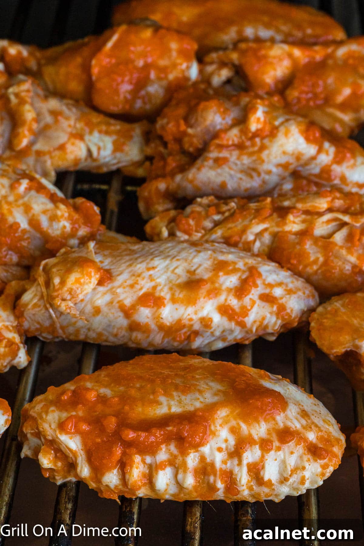Buffalo Sauce coated chicken wings placed on the grill grates